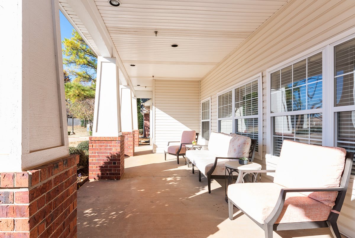 A sunny porch with comfortable outdoor seating and brick pillars.