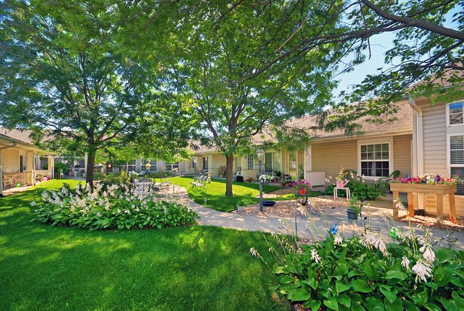 A serene garden with lush greenery and a sunlit pathway leading to a cozy house.
