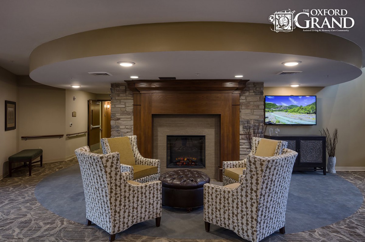 A cozy lounge area featuring a fireplace, armchairs, and a television.