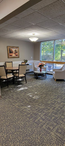 A cozy living area featuring a dining table, chairs, and comfortable seating by a large window.