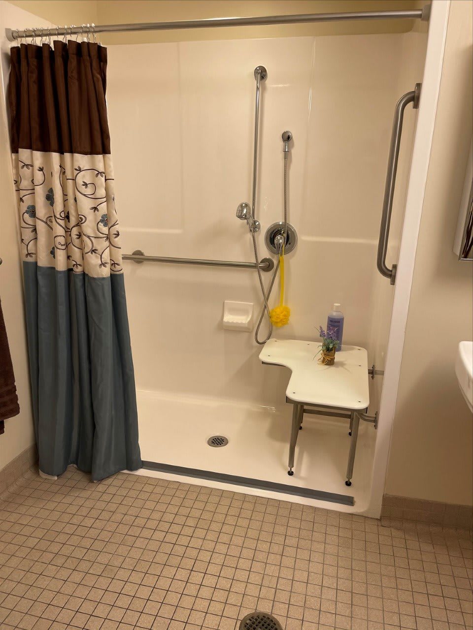 An accessible bathroom shower with a seat and grab bars, designed for ease of use.
