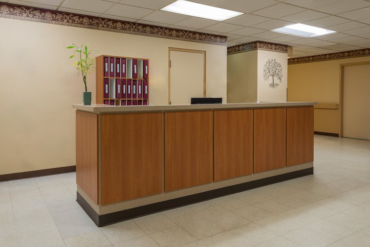 A reception desk in an office setting with wood paneling and neutral decor.