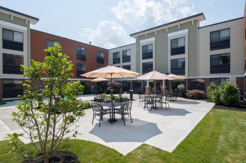 A modern outdoor patio area with tables and umbrellas at the back of a building.