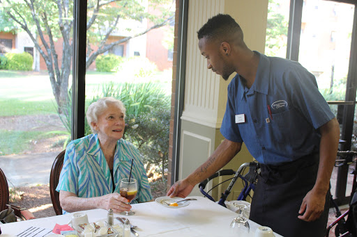 A server attending to an elderly customer in a dining setting.