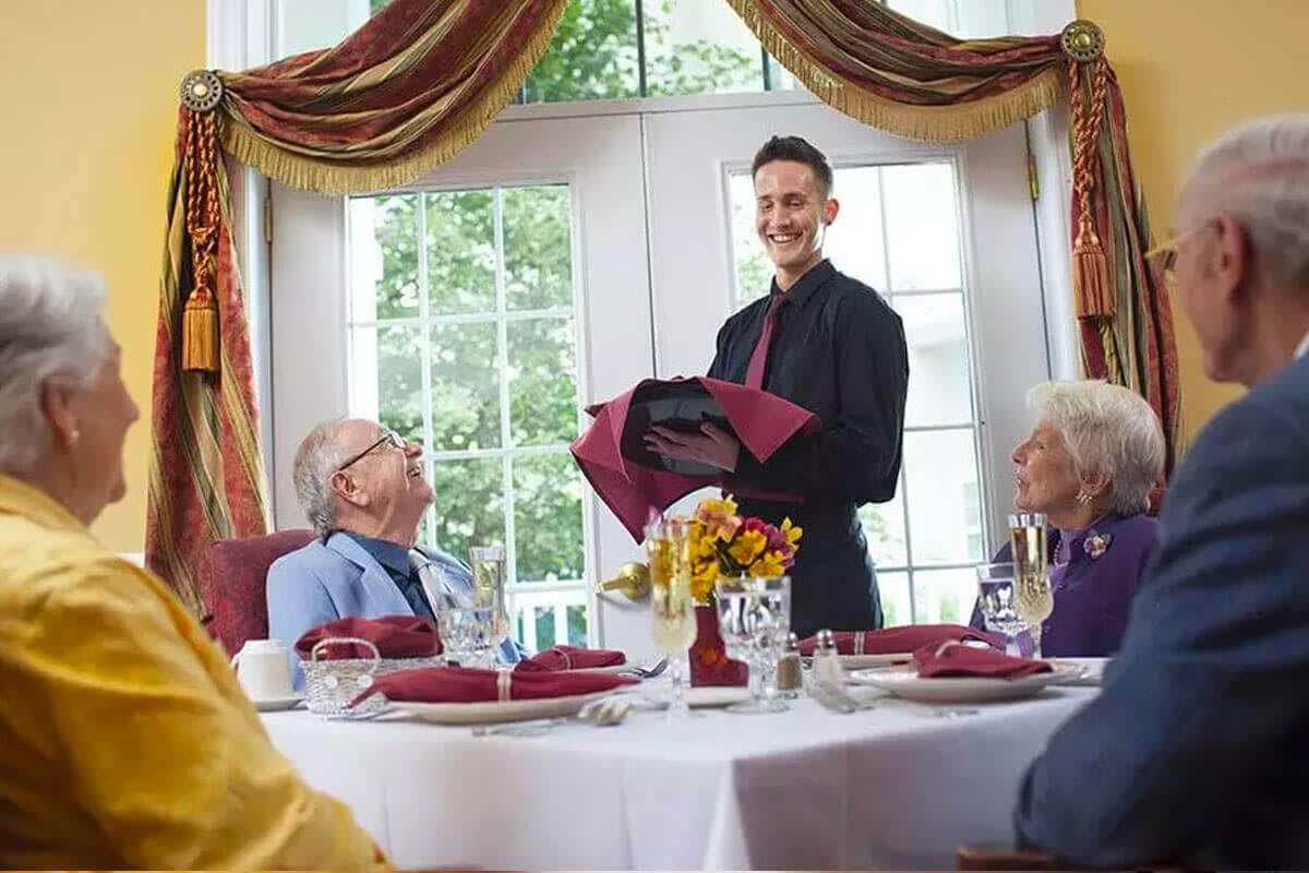 A waiter serves guests at a restaurant table with a formal setting.