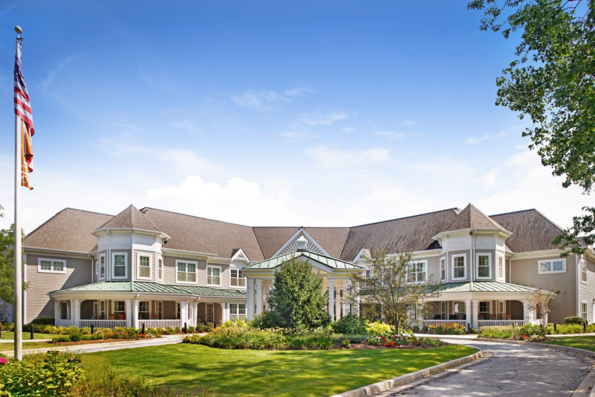 A large, elegant residential building with a well-maintained garden and clear blue sky.