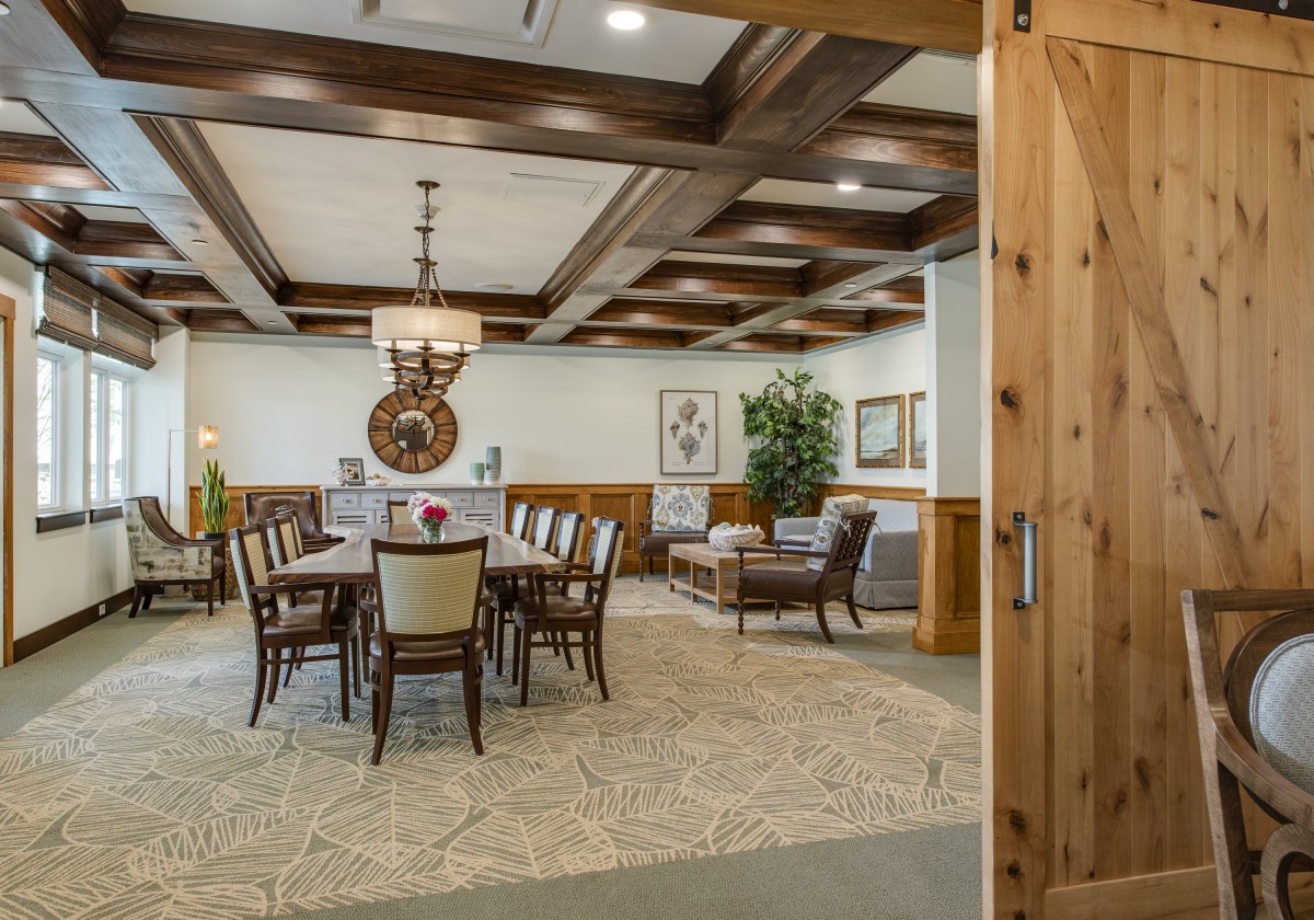 A well-furnished dining room with a large table and chairs, featuring wooden ceiling beams and elegant decor.