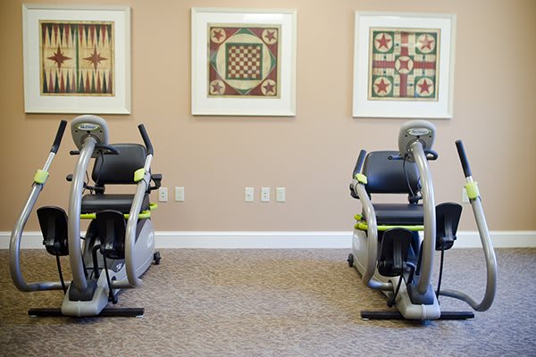 A gym room featuring two stationary bikes and framed artwork on the walls.