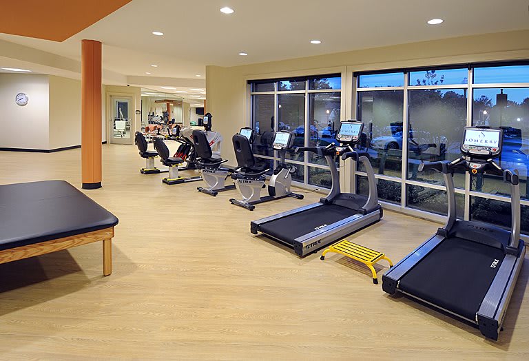A modern gym with treadmills and exercise machines overlooking large windows.