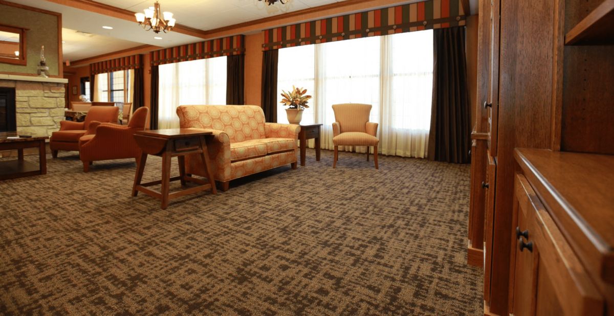 A cozy living room with a sofa, chair, and coffee table on a patterned carpet.