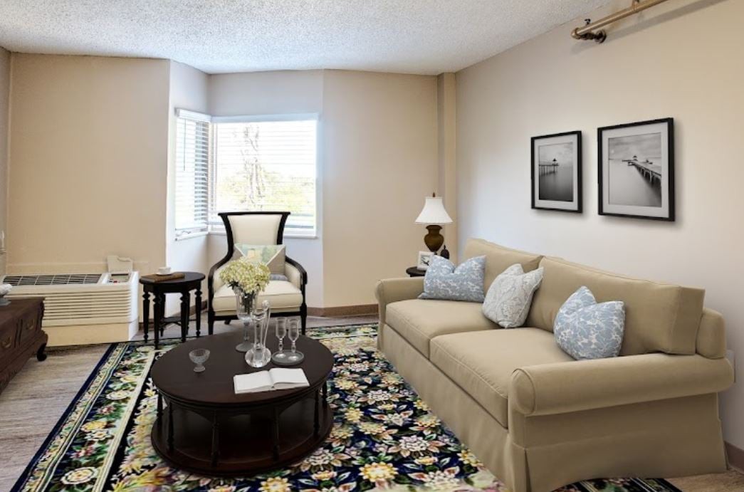 A cozy living room with a beige sofa, armchair, and floral rug.