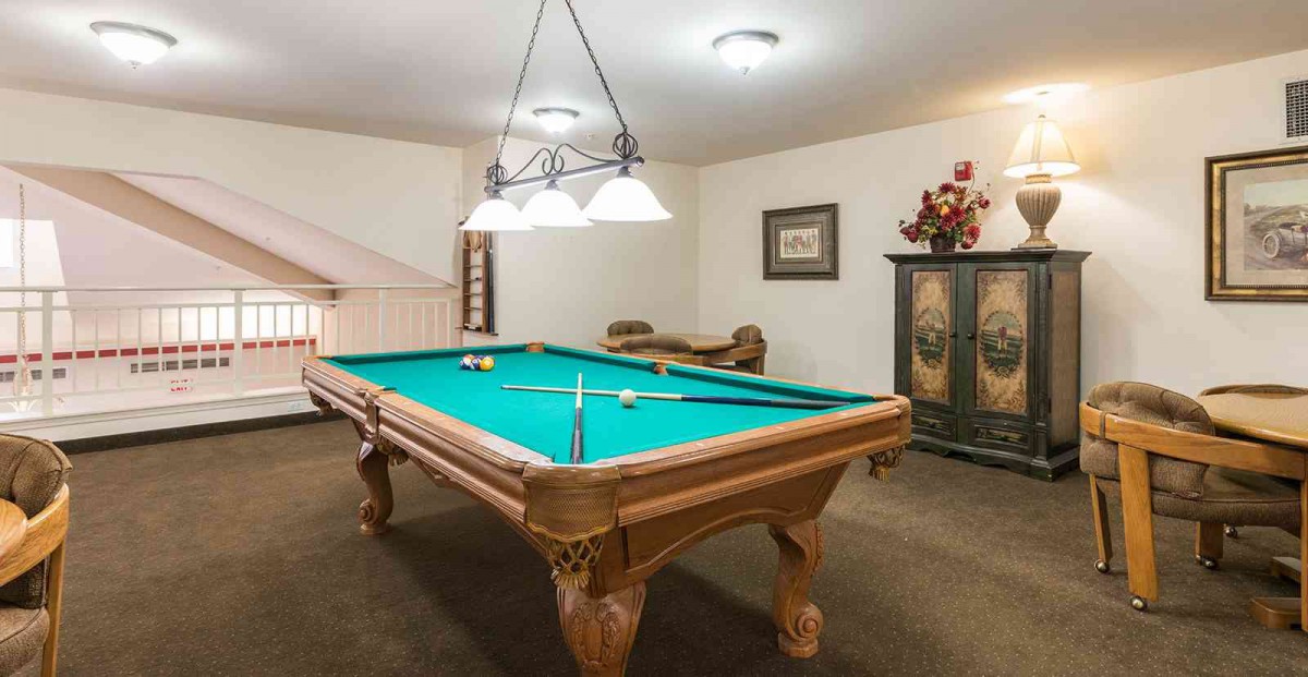 A cozy recreation room featuring a classic pool table under warm lighting.