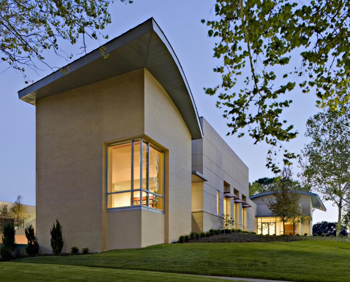 A modern building with large windows, showcased in the evening light.