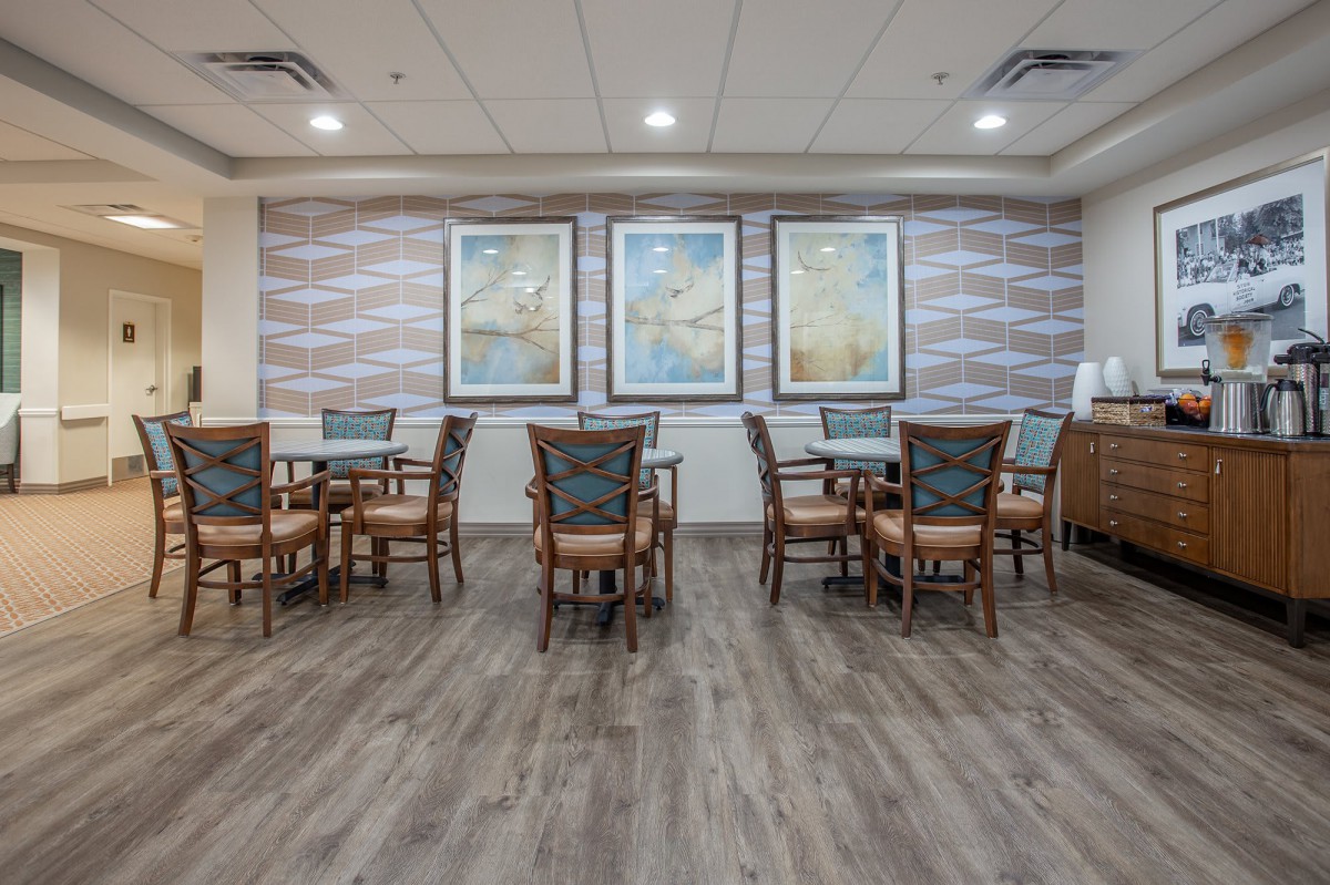 A dining area with tables and chairs, decorated with artwork on the walls.