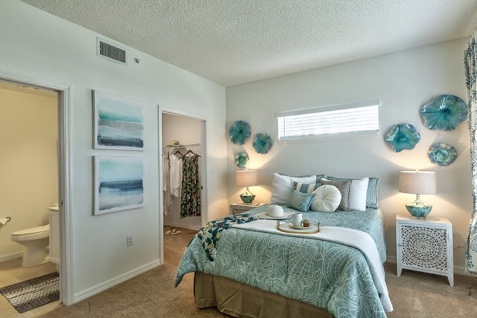 A modern bedroom with elegant decor, featuring a neatly made bed and artistic wall accents.