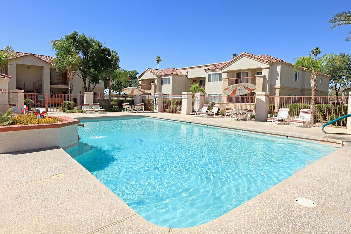 A sunny day at a residential apartment complex featuring an inviting outdoor swimming pool.