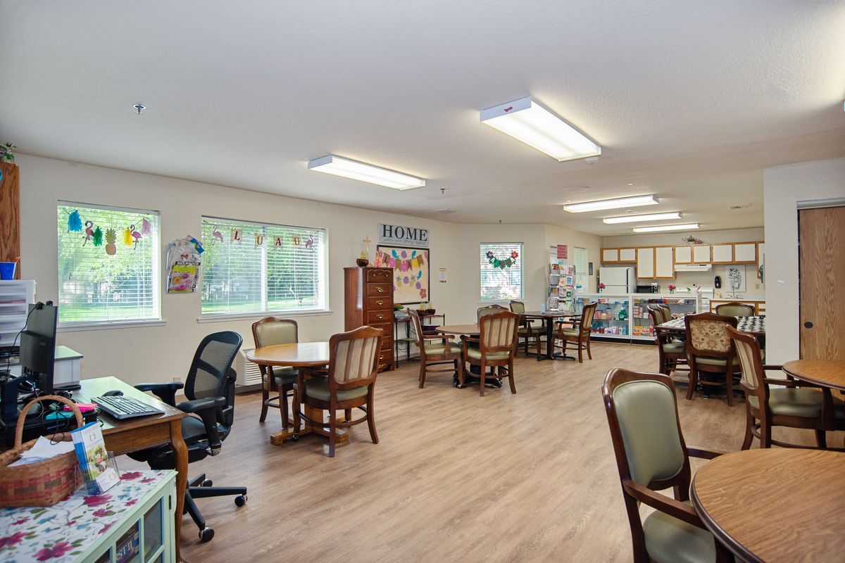 A well-lit classroom with tables, chairs, and bright windows.
