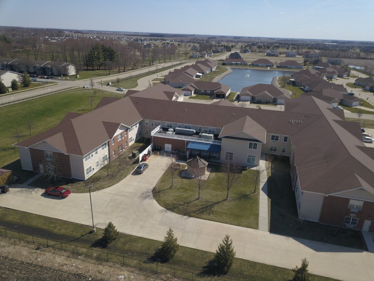 Aerial view of a suburban residential area with buildings and a pond.