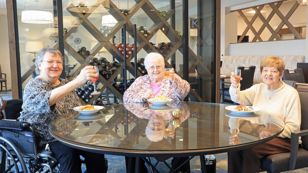 A group of elderly people enjoying a meal together at a round table in an indoor setting.