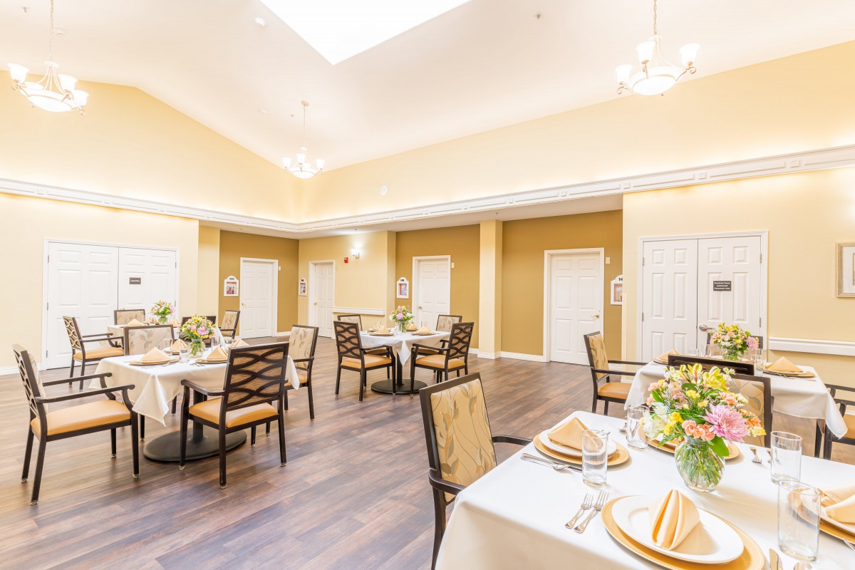 An elegantly decorated dining room with neatly arranged tables and chairs under bright lighting.