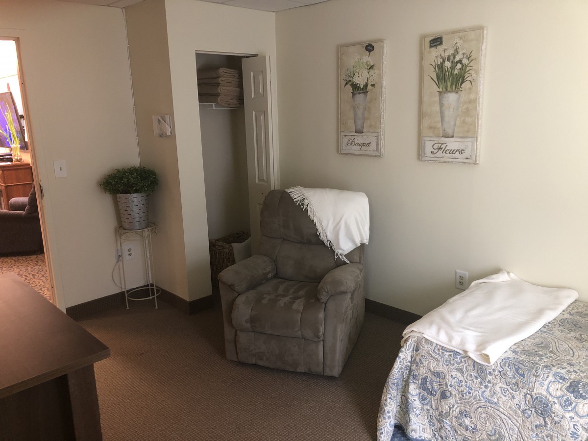 A cozy room featuring a comfortable armchair, bed, and decorative wall art.