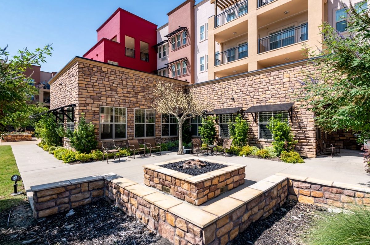 A modern apartment complex featuring a stone facade and a central courtyard with a fire pit.
