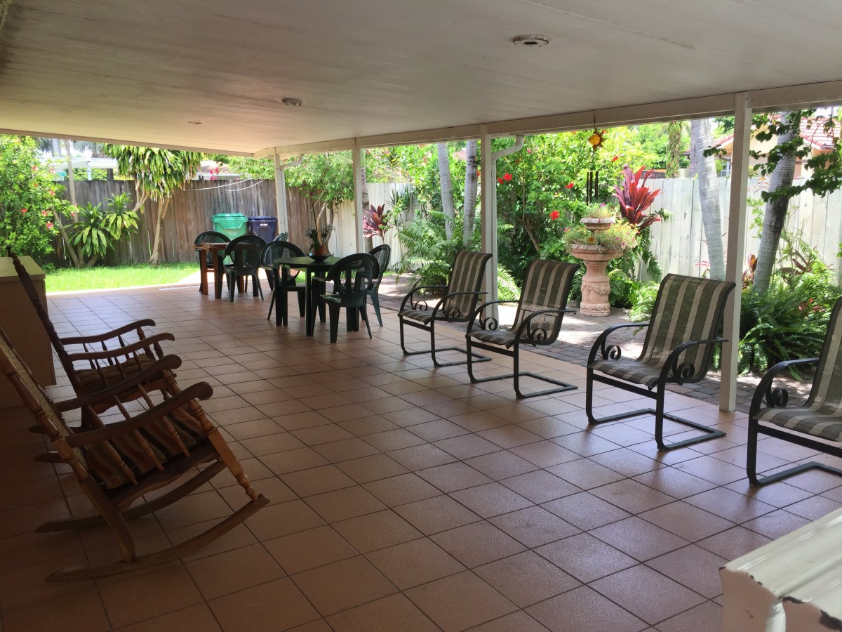 A spacious covered patio with chairs and a table, overlooking a lush garden.