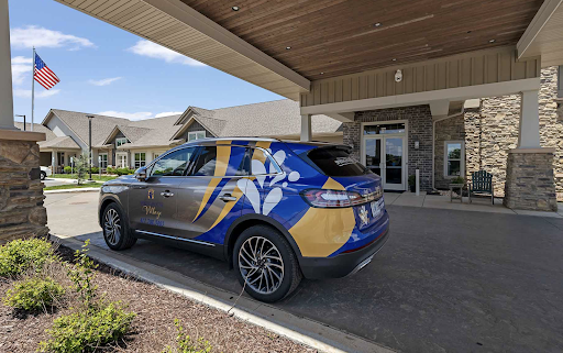 A branded vehicle parked outside a building, featuring a blue and yellow design.