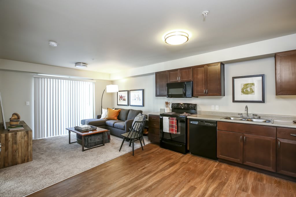 A modern open-concept living room with a kitchen, featuring hardwood floors and stylish decor.