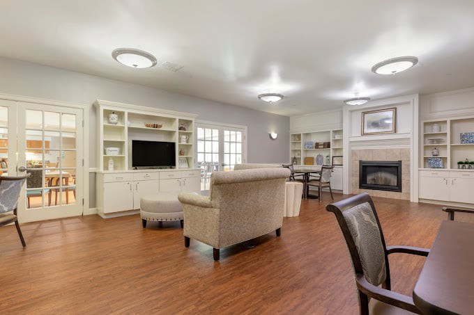 A spacious and modern living room featuring cozy furniture, a fireplace, built-in bookshelves, and a large television.