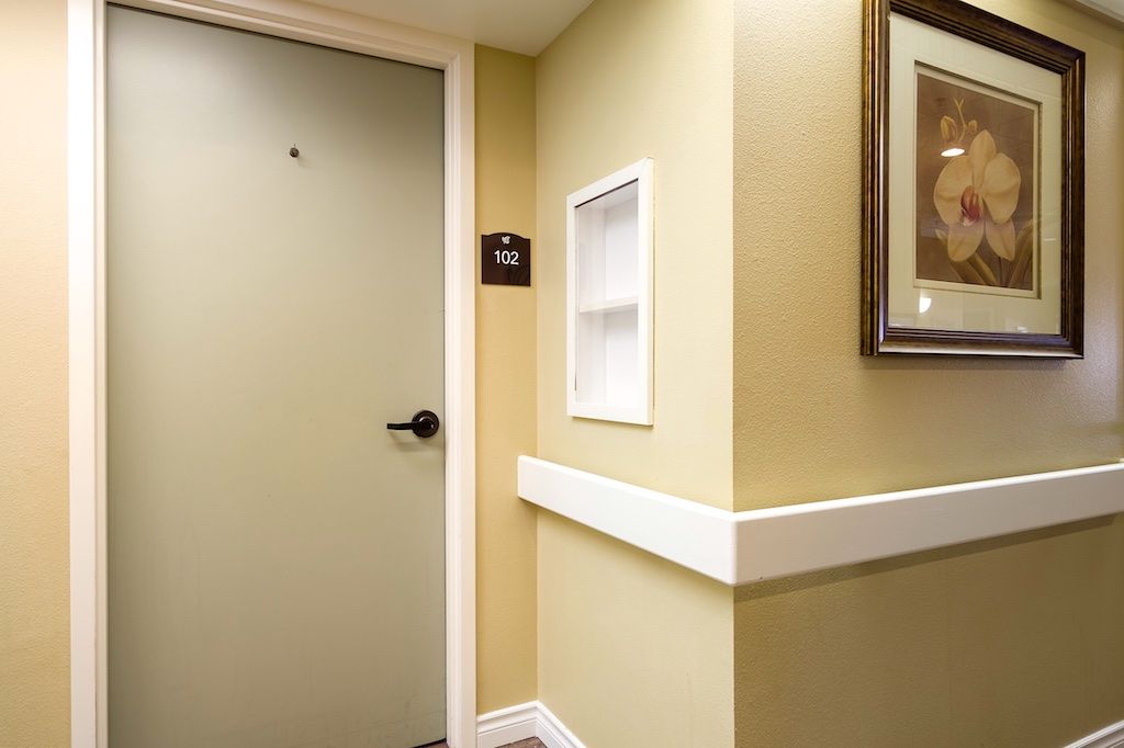 A hallway with a closed door, framed picture, and light switch.