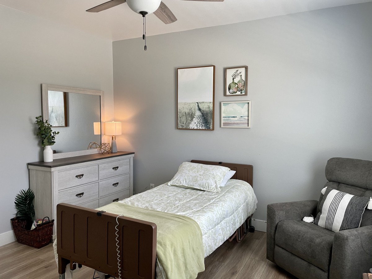 A modern minimalist bedroom with a single bed, dresser, and wall art.