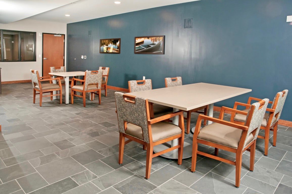A modern dining area with tables and chairs arranged neatly against a blue accent wall.