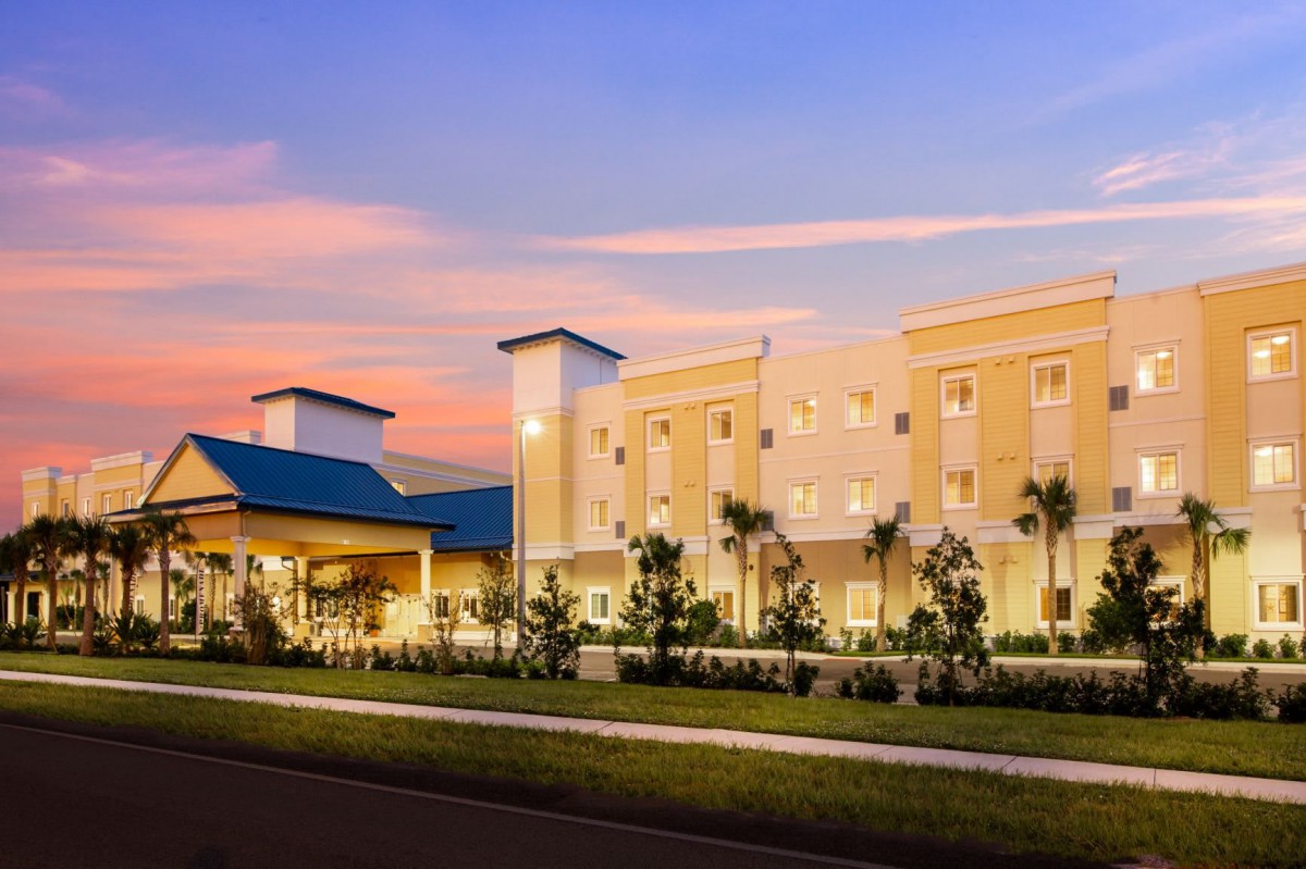 Modern hotel building at sunset with landscaped surroundings.