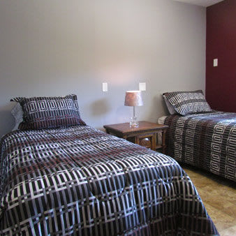 A cozy bedroom featuring two twin beds with geometric patterned bedding and a shared nightstand with a lamp.