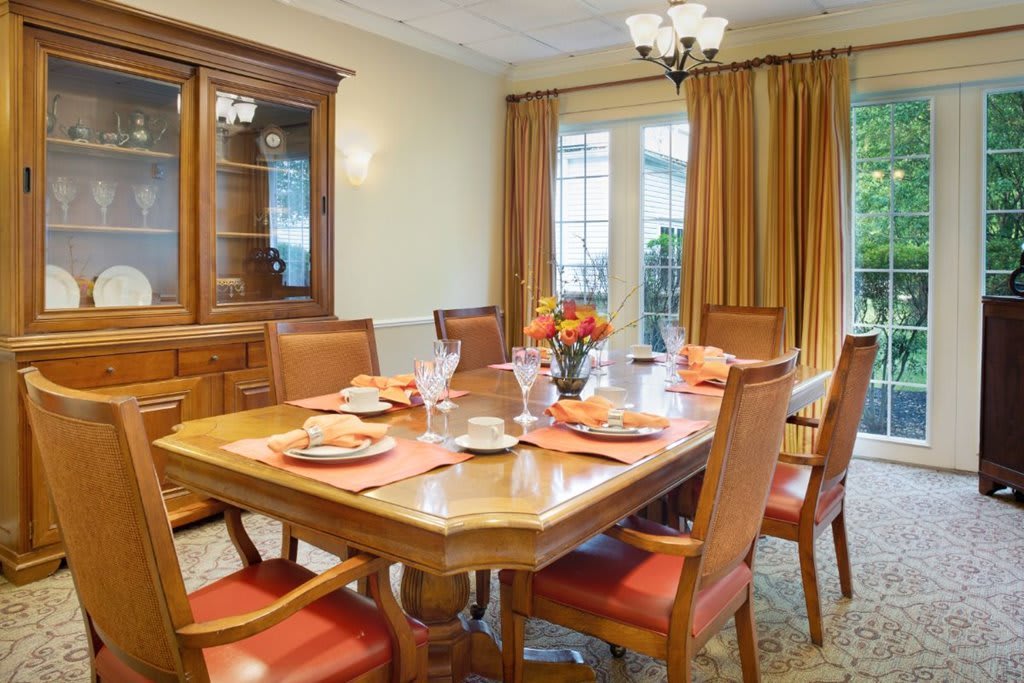 A well-appointed dining room with a wooden table and chairs, complemented by elegant curtains and a chandelier.