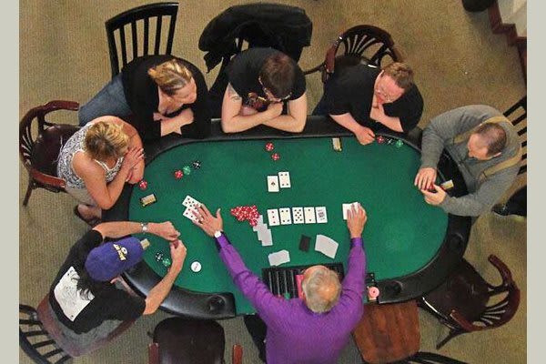 A group of people playing poker at a casino table.