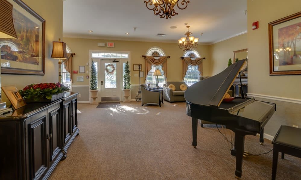 A spacious living room featuring a grand piano, elegant chandeliers, and classic furnishings.
