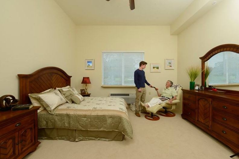 A comfortable bedroom scene with two people engaged in conversation.