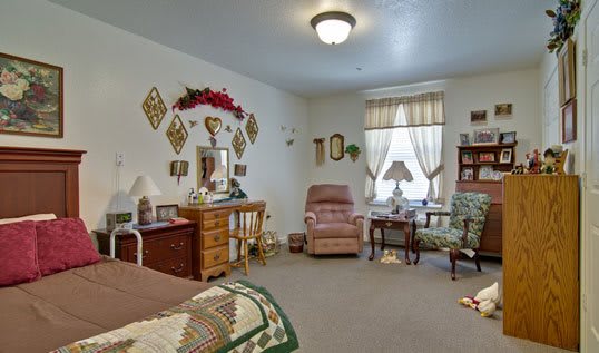 A cozy living room with vintage furniture and decor, featuring a comfortable armchair and a well-decorated dresser.