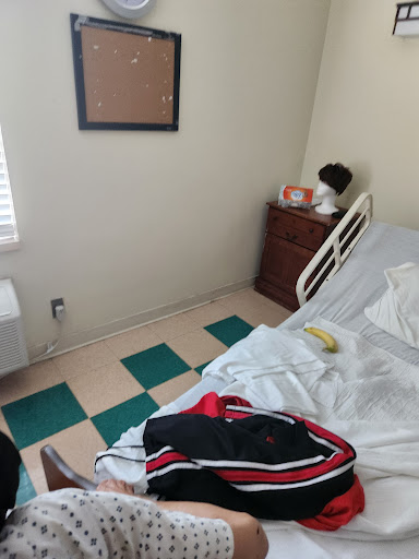 A room featuring a medical bed, some personal items, and an unmade bed with a banana on it.