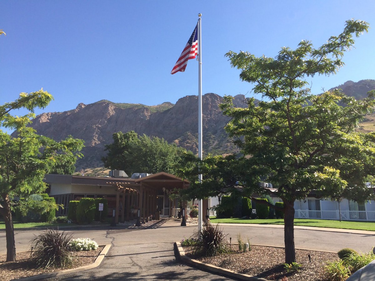 An American flag flying in front of a building with mountains in the background.