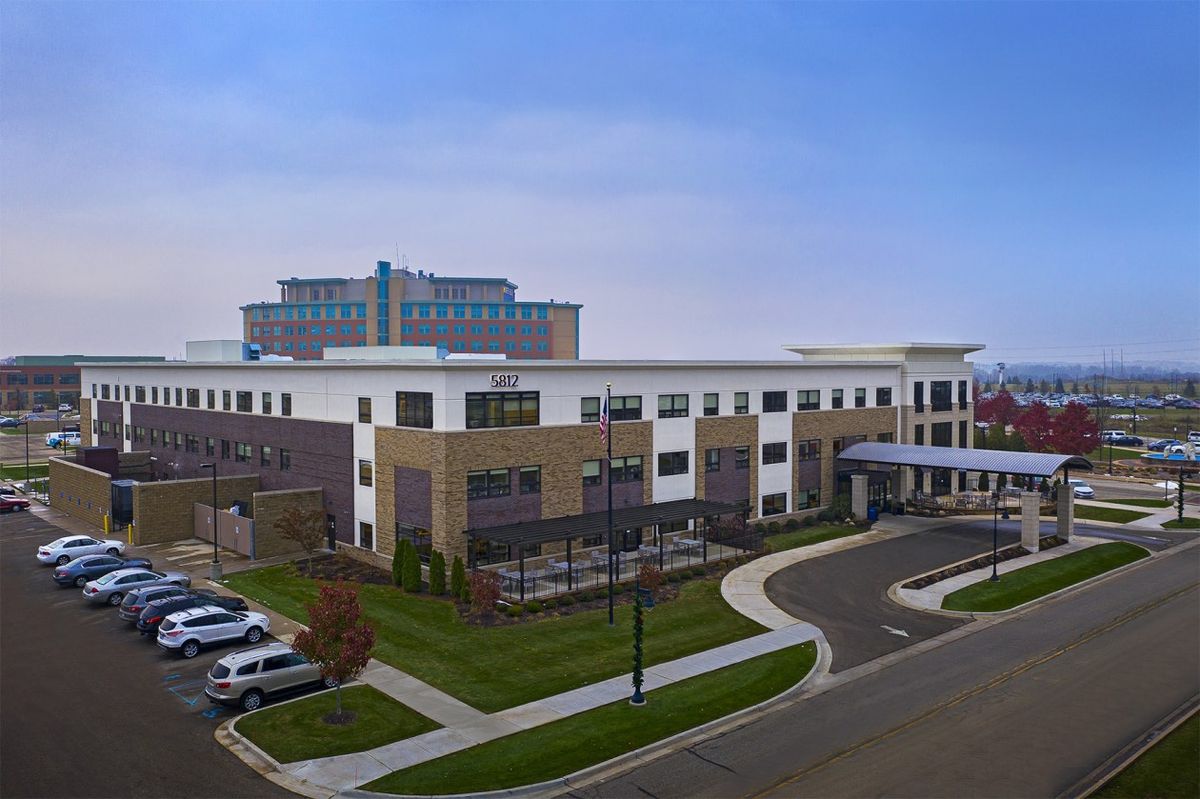 A modern office building with a surrounding parking area and landscaped grounds.