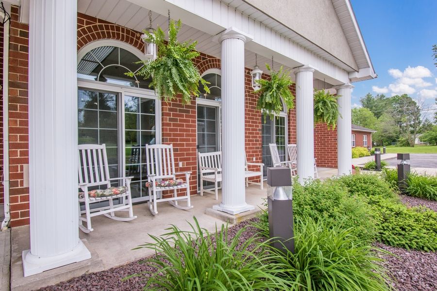 A charming porch with rocking chairs, large columns, and hanging ferns.