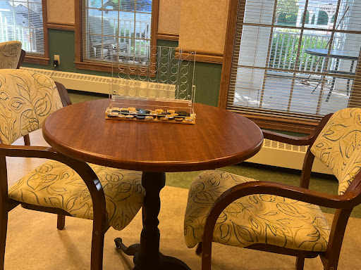 A cozy dining area featuring a wooden table and patterned chairs, illuminated by natural light from the windows.