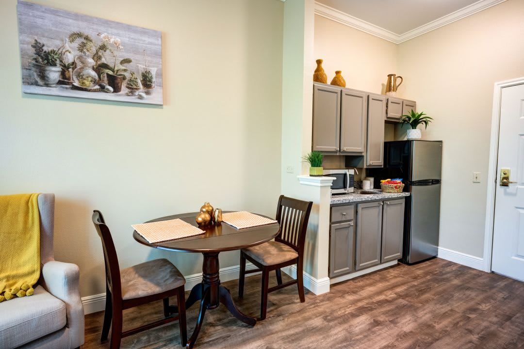 A cozy dining area adjacent to a small kitchen with wooden cabinetry and modern appliances.