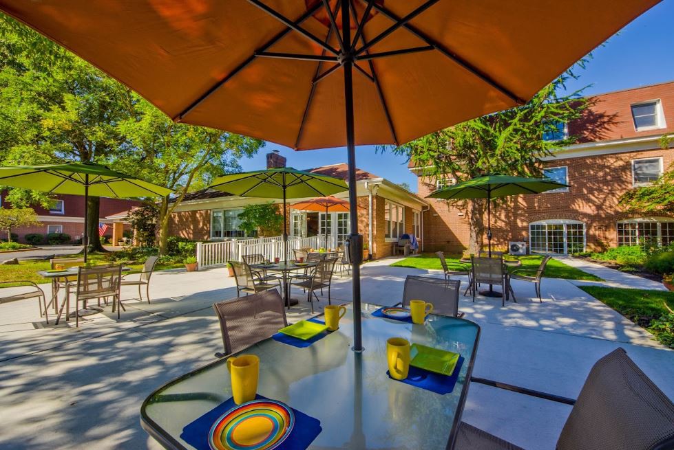An inviting outdoor patio area with tables set for dining under colorful umbrellas.
