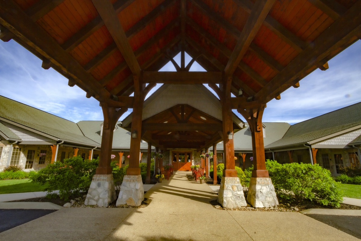 A grand wooden entrance with a covered walkway and decorative columns.