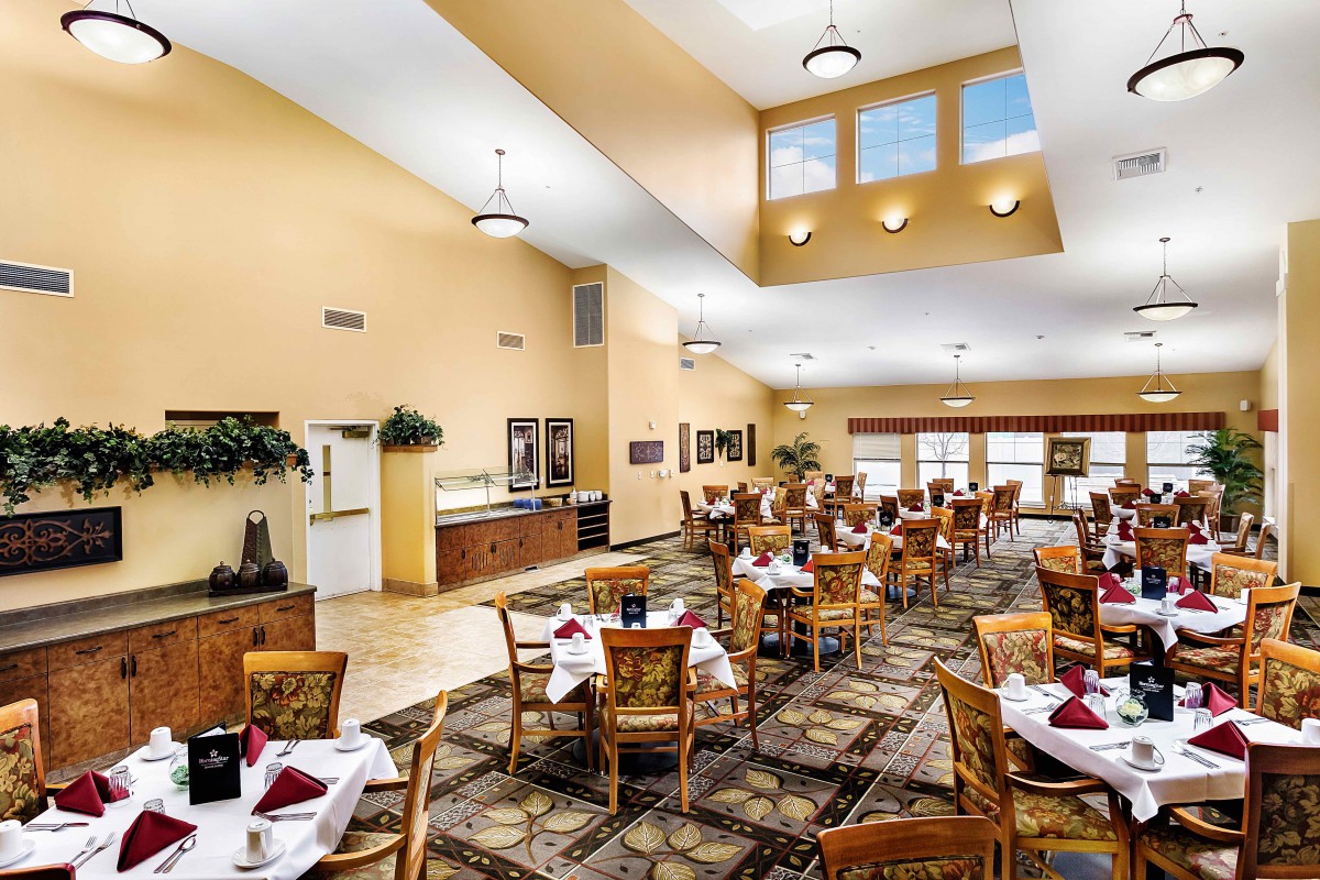 Spacious dining area with neatly arranged tables and chairs, featuring warm lighting and decorative elements.