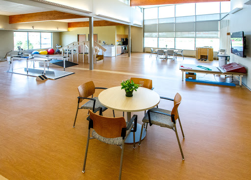 A spacious and well-lit interior of a rehabilitation center, featuring a simple table surrounded by chairs.